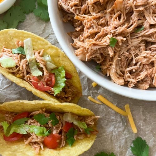 3 ingredient slow cooker mexican shredded chicken in bowl with 2 tacos