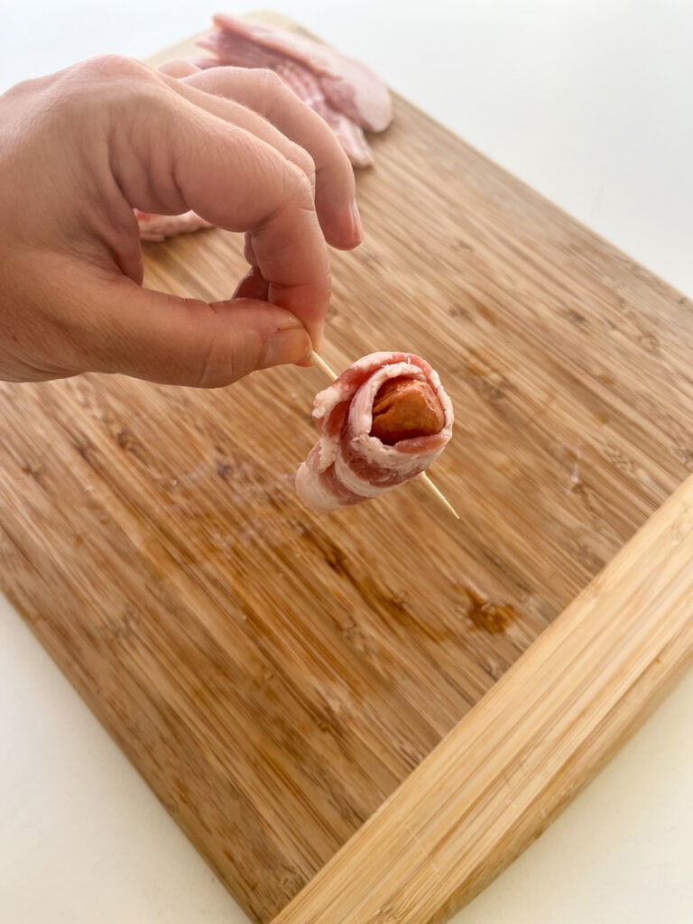 bacon wrapped smokie with toothpick through it