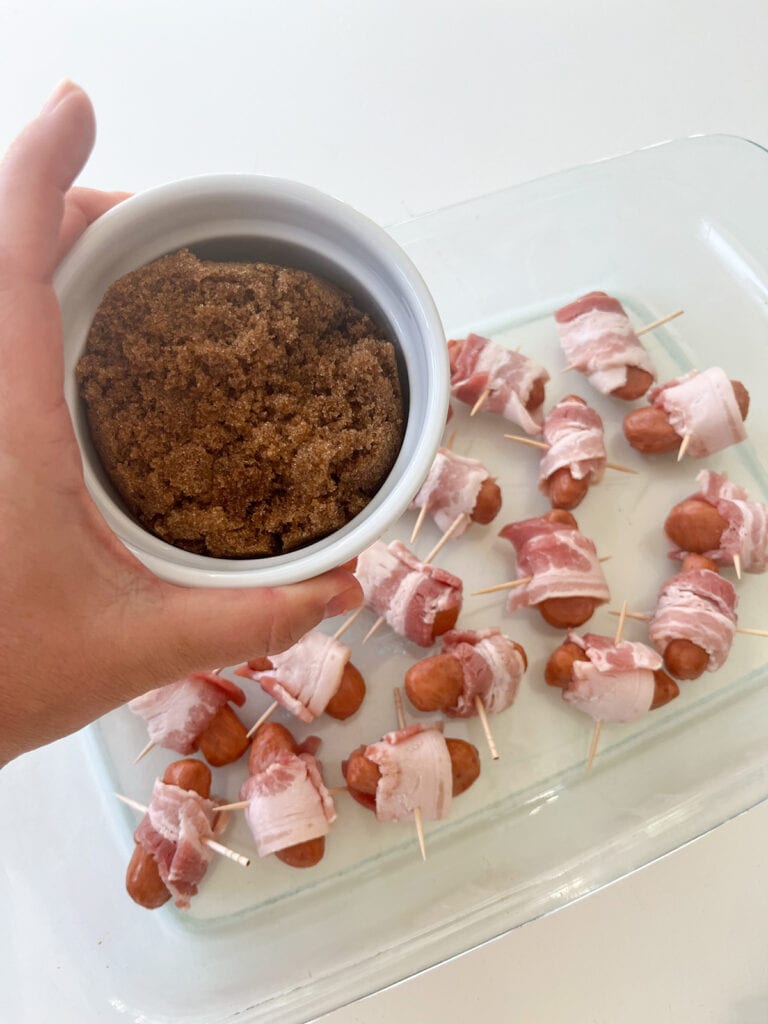 Bacon Wrapped Little Smokies in baking dish with bowl of brown sugar