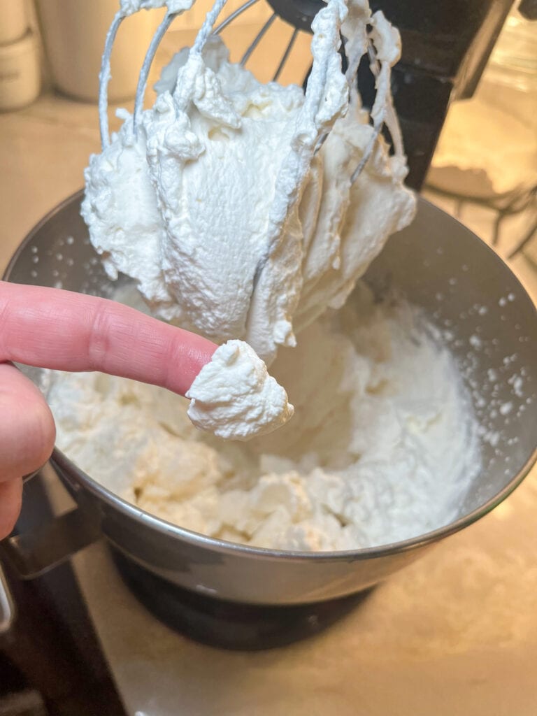 whipped cream on a finger in front of mixing bowl