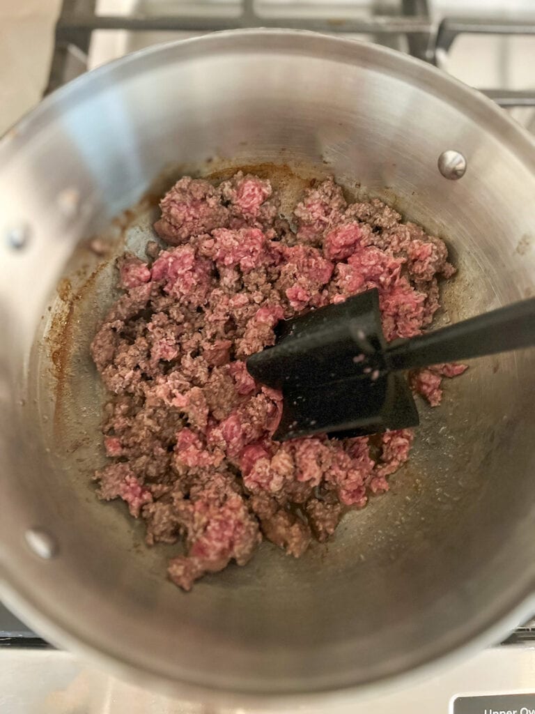 browning ground beef in pot on stove using a meat crumble tool