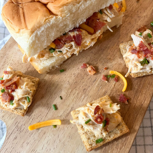 Slow Cooker Creamy Ranch Chicken With Bacons served on a roll and on crackers on a wooden tray