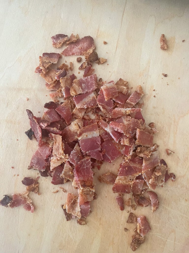 chopped, cooked bacon on a wood cutting board