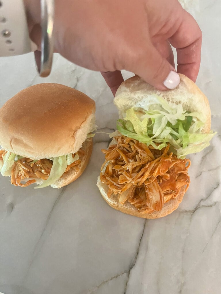adding shredded lettuce to sliders and placing bun on top