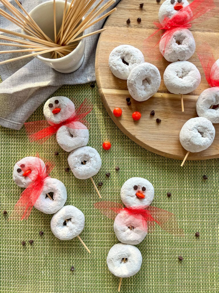 Donut Snowman Skewers on a green and wooden background