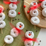 Donut Snowman Skewers laying on green and wooden background