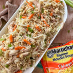 Chinese Chicken Salad Recipe with Ramen Noodles in a oblong white serving bowl on a mauve pink napkin with a package or Ramen noodles next to it