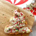 one Christmas Cinnamon Roll on a wood background with sprinkles spilling