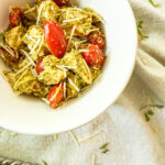 With juicy chicken and flavorful Pesto, this 4 ingredient Pesto Chicken Salad recipe is a low-carb, high protein power meal that will keep you full for hours. This image shows it being served in a white bowl with extra parmesan cheese and fresh basil sprinkled around.
