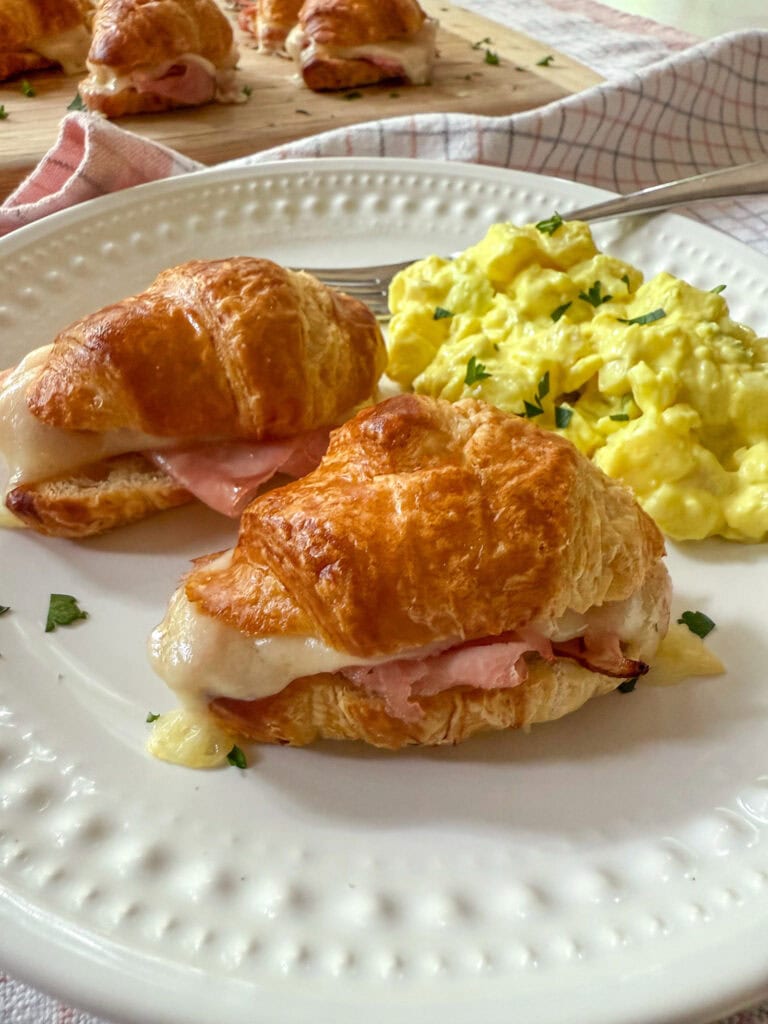Mini Ham and Cheese Croissant Sandwiches on a white plate with a side of potato salad