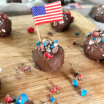 Patriotic Peanut Butter Bon Bons on a wood serving tray with a grey napkin background