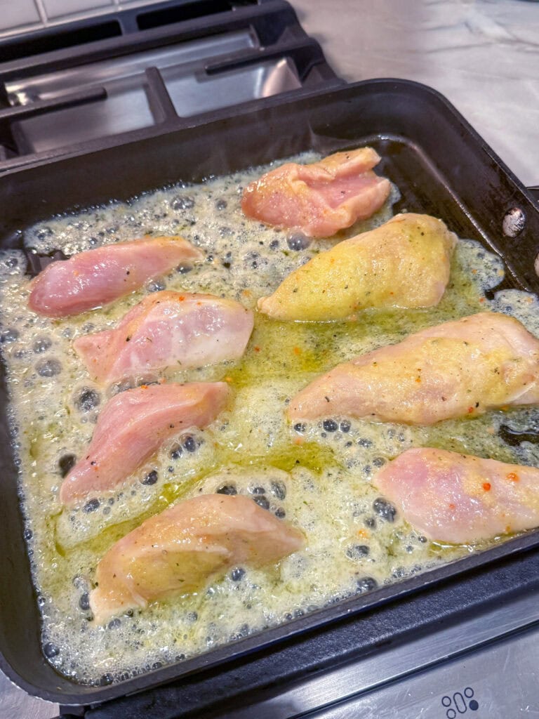 chicken strips cooking in griddle pan