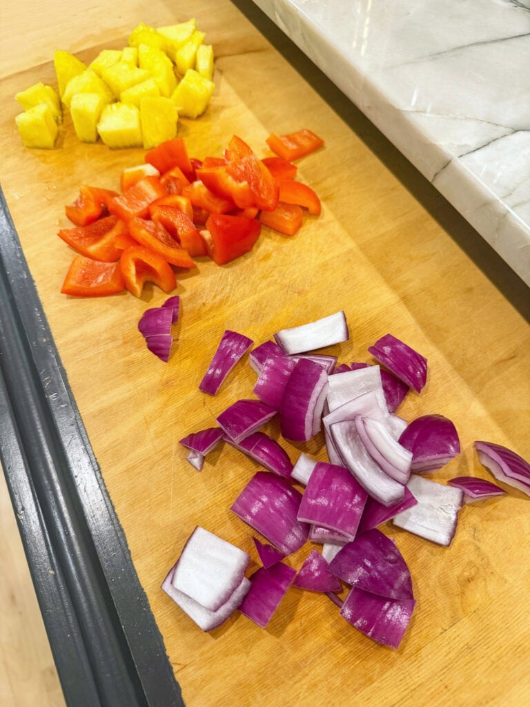 chopped pineapple, red pepper and red onion on cutting board