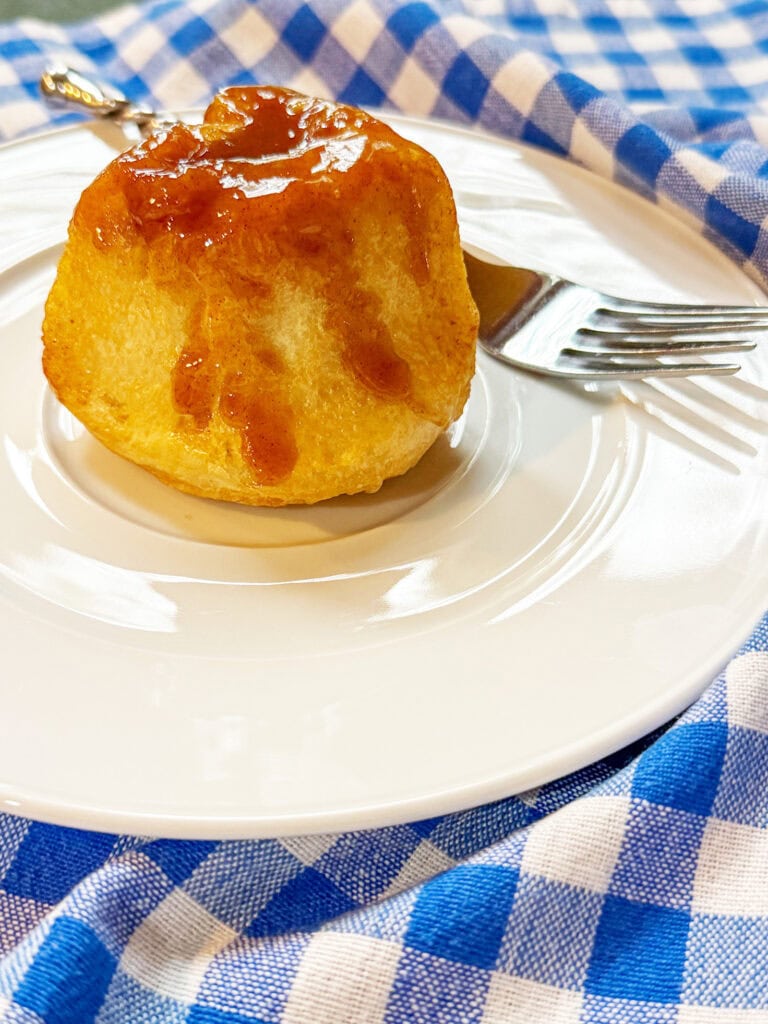one Overnight Caramel Rolls on a white plate with a fork and a blue and white check napkin.