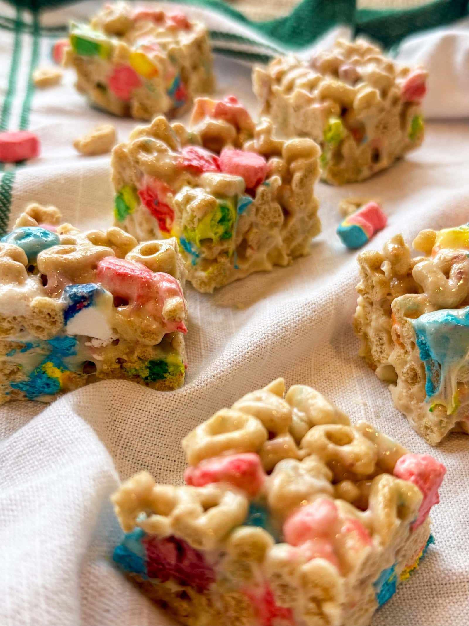 Lucky Charms Cereal Bars cut into squares on a white and green napkin ready to serve at a party