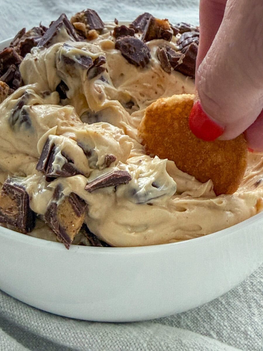 a Nilla Wafer being dipped into a bowl of Reese's Peanut Butter Cup Dip