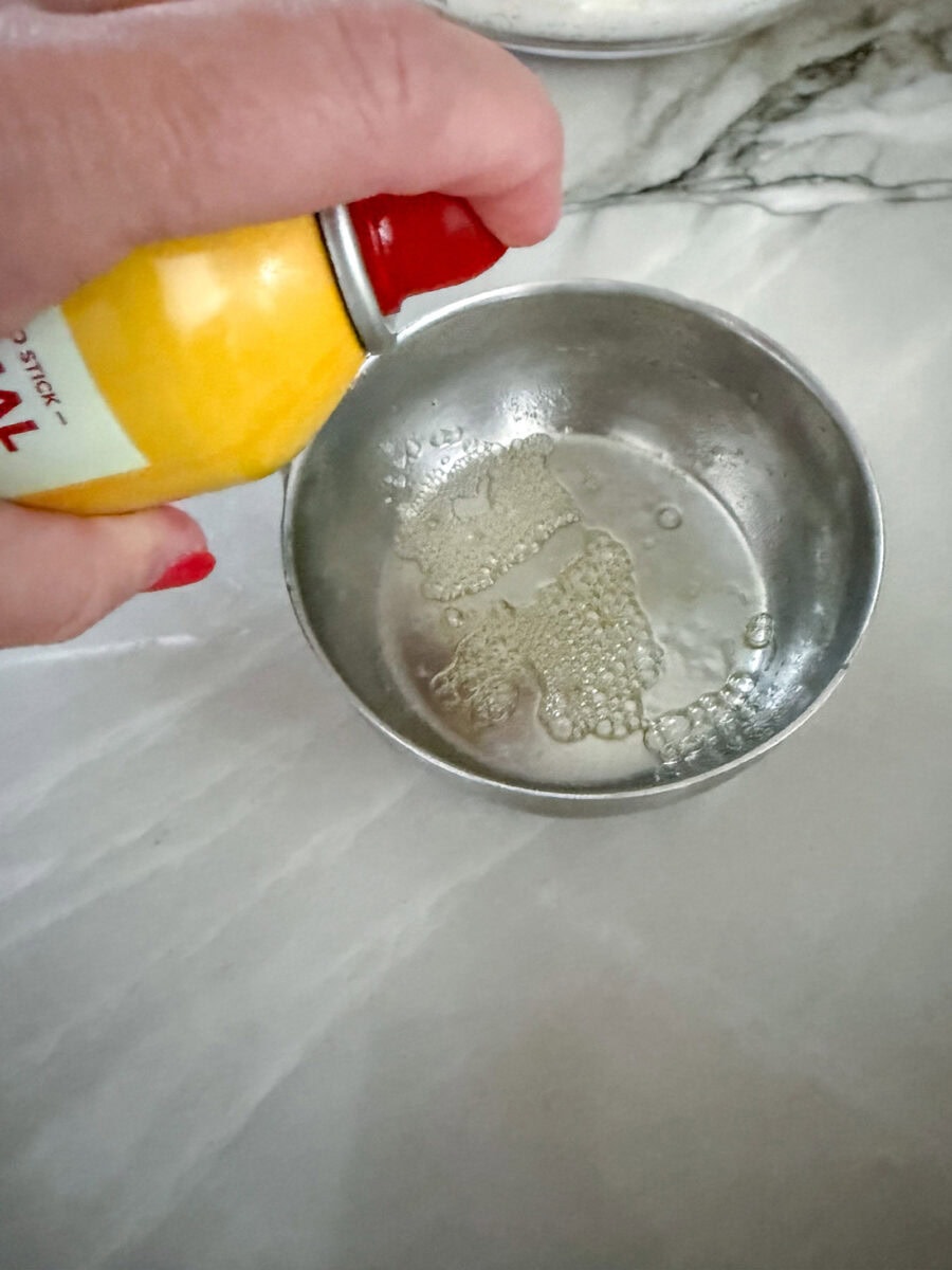 spraying a measuring cup with cooking spray so peanut butter won't stick to it