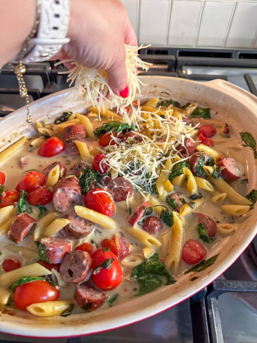 topping Spinach and Artichoke Dip Pasta Bake with Chicken Sausage with shredded parmesan cheese