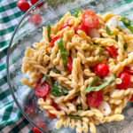 Caprese Pasta Salad in a glass bowl on a green and white check napkin