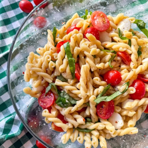 Caprese Pasta Salad in a glass bowl on a green and white check napkin