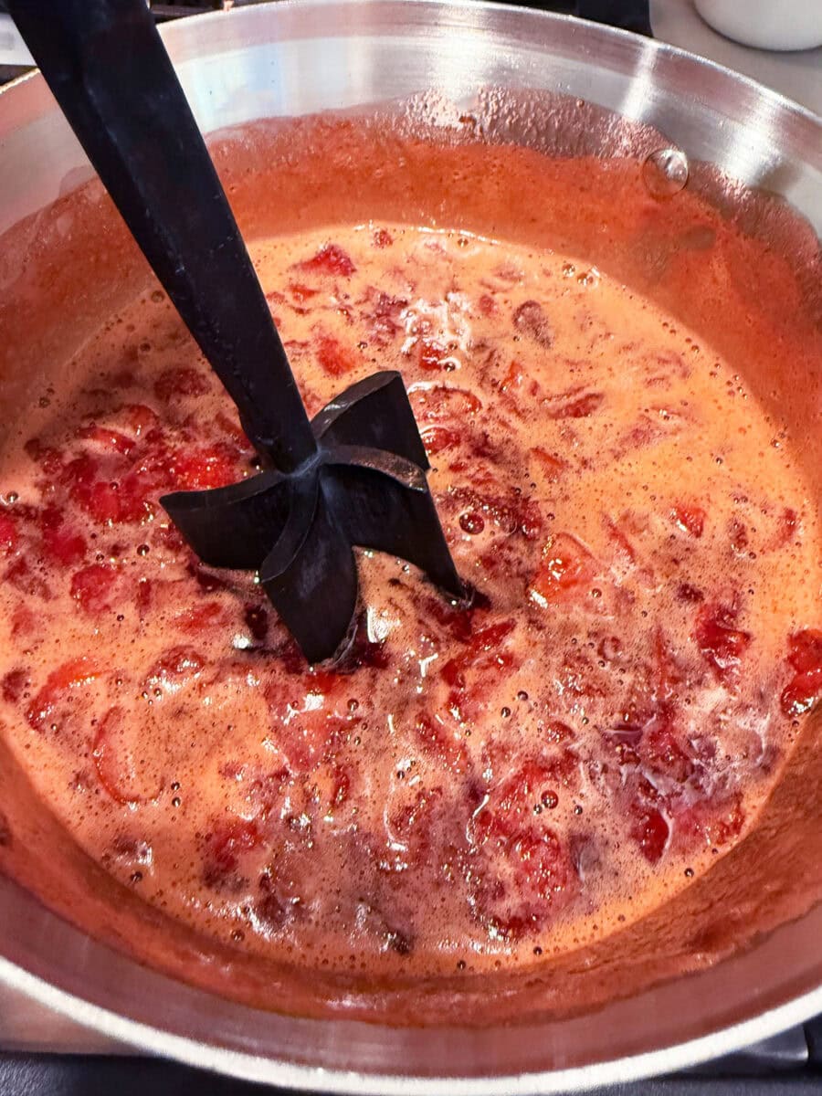 mashing berries as the cook in saucepan for homemade strawberry jam