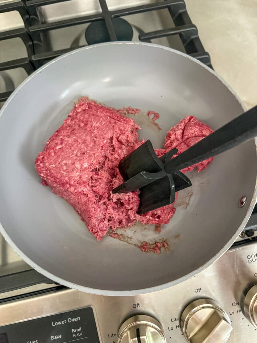 browning beef in fry pan with meat chopper