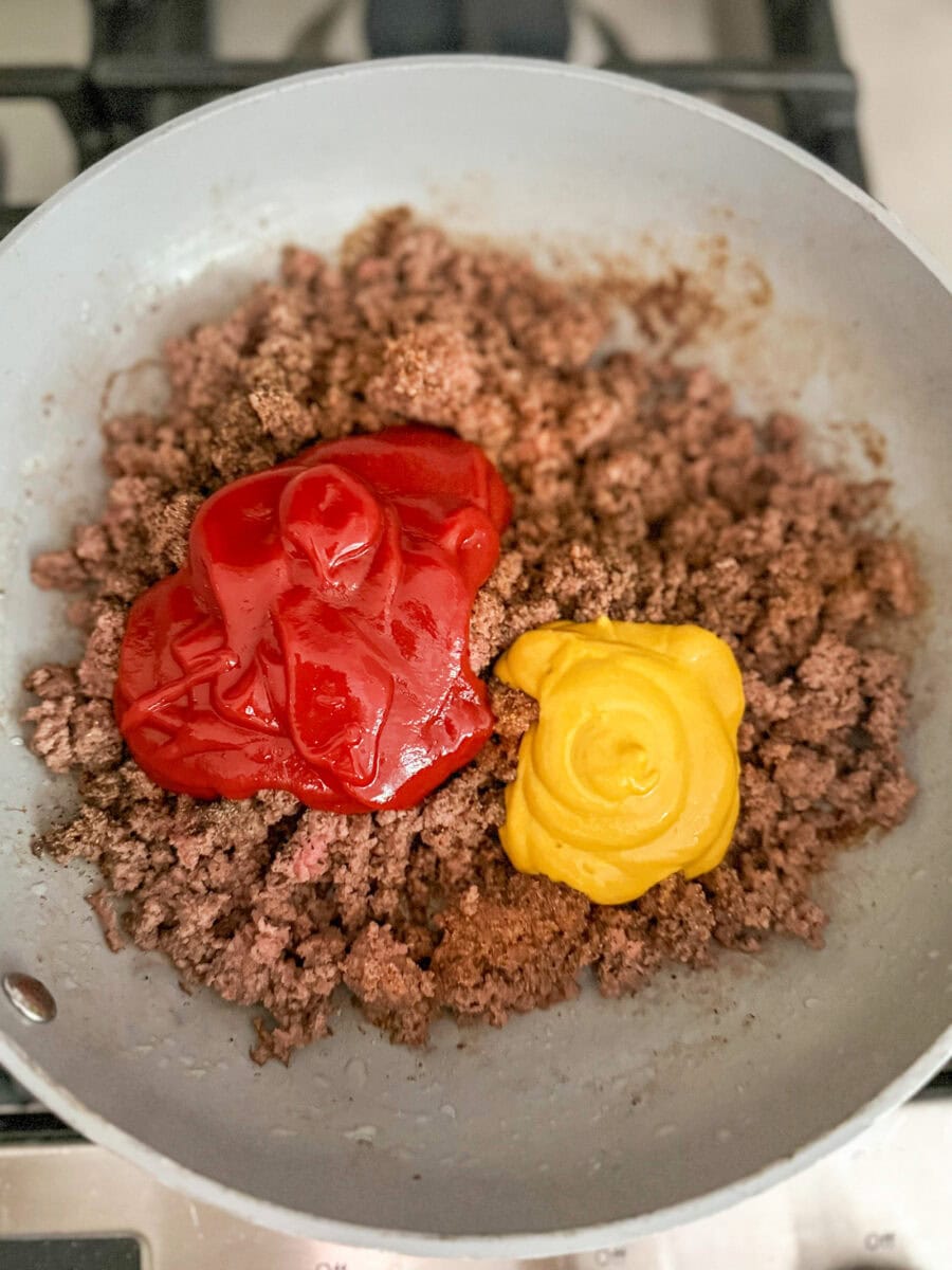 adding ketchup and mustard to meat mixture