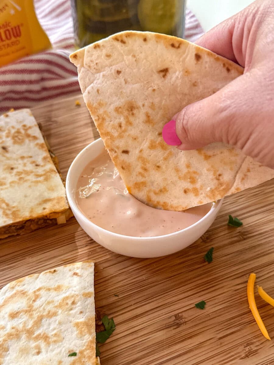 dipping cheeseburger quesadilla in homemade dipping sauce