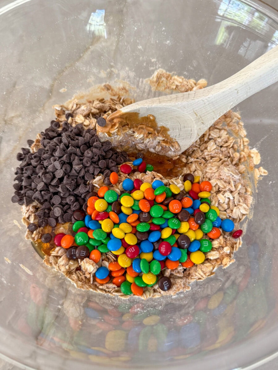 add mini M&Ms and mini chocolate chips to oat mixture in large glass bowl