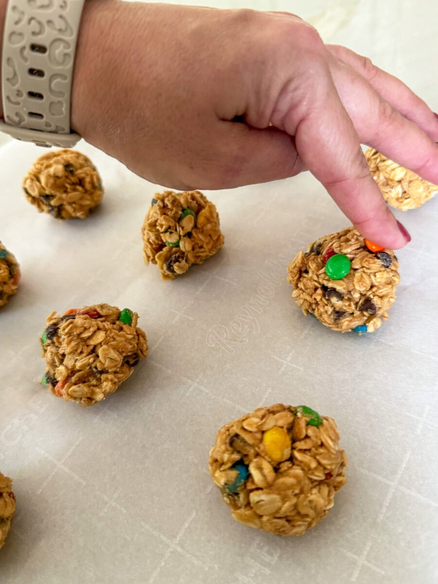 hand pressing extra mini M&M candy into Monster Cookie Protein Balls